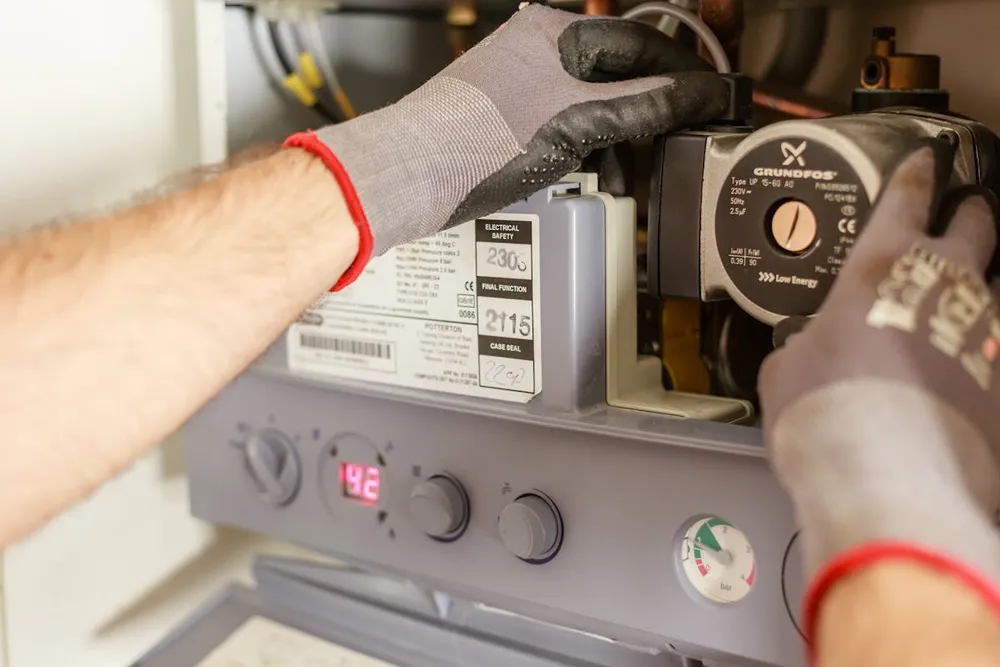 Technician servicing a gas furnace and checking the heat exchanger