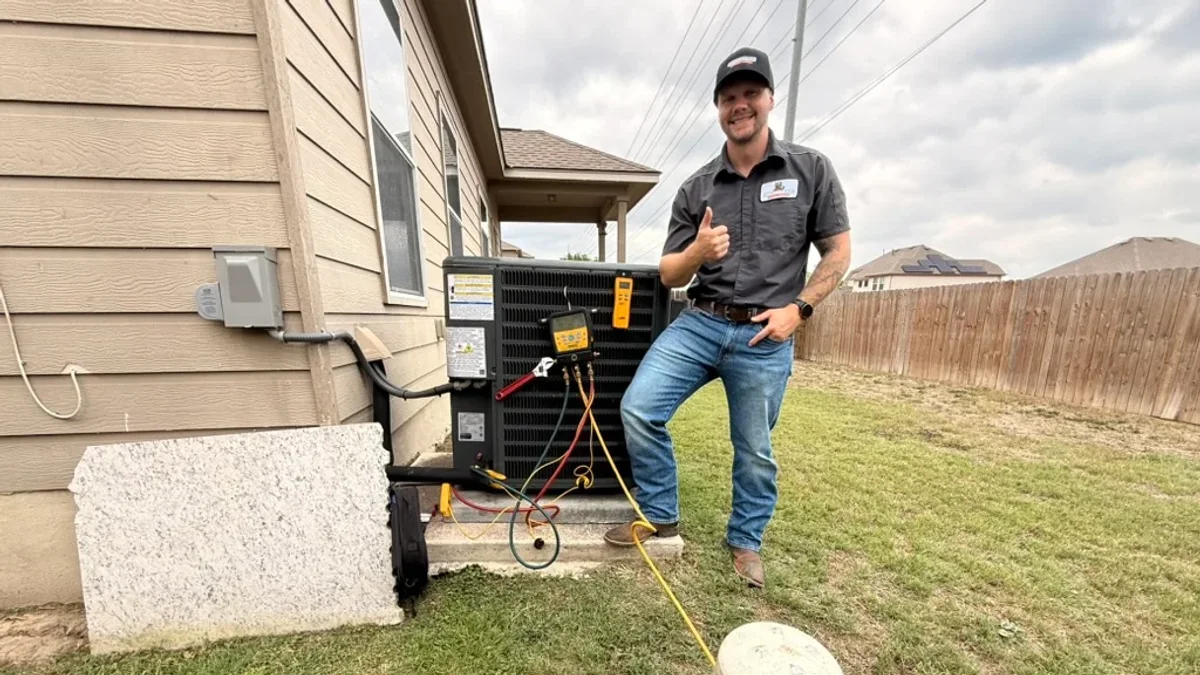 A Moorhead Service Company technician testing the electrical side of an outdoor AC condenser unit, where the run capacitor lives, at a New Braunfels home.