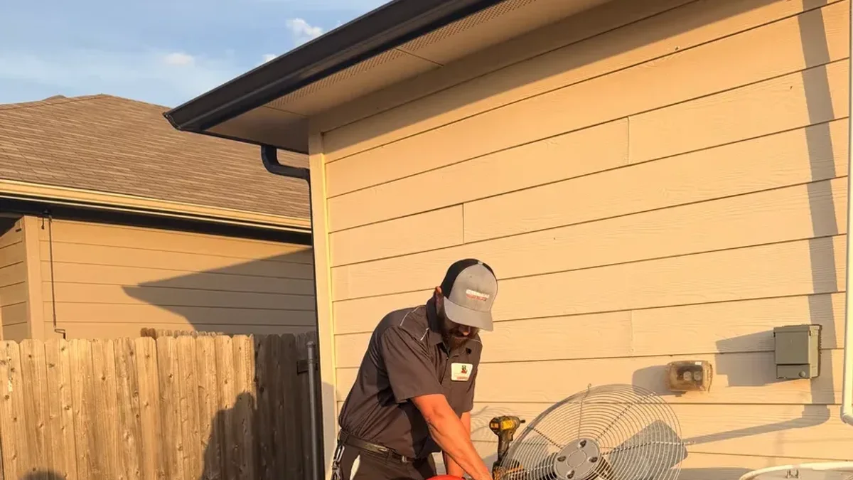 A Moorhead Service Company technician servicing an outdoor AC condenser unit at a home near New Braunfels, Texas.